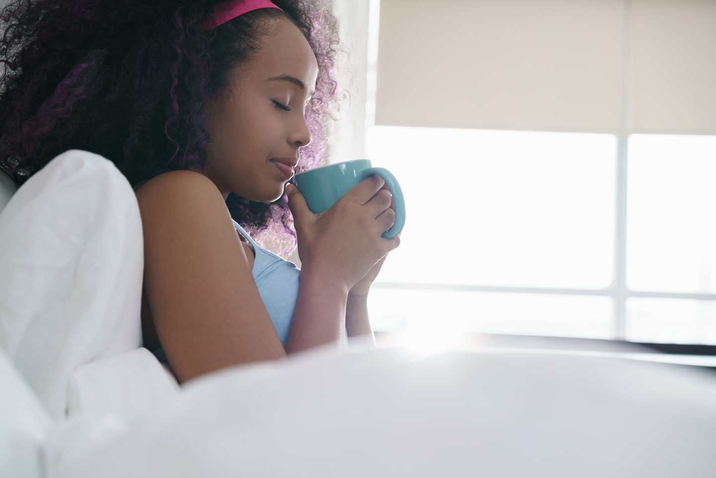 Black Woman Drinking Coffee in Bed Smiling